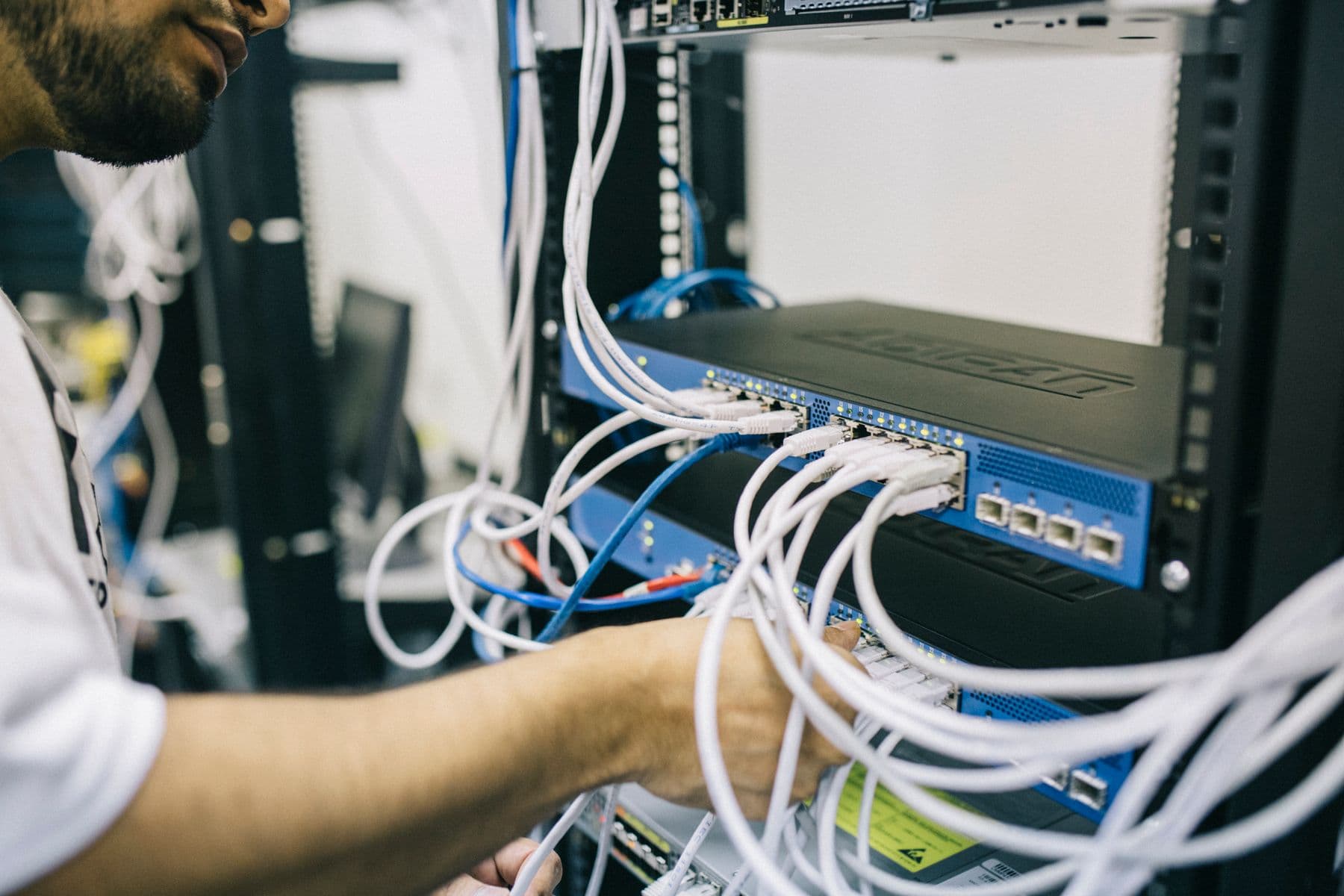 Technician dressing a network switch — illustrative, not a Converge site